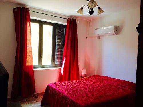 1 dormitorio con cortinas rojas, 1 cama y ventana en Pericle apartment, en Taormina