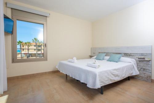 een slaapkamer met een groot wit bed en een raam bij Joan in Can Picafort