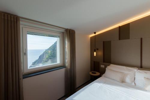 een slaapkamer met een bed en een groot raam bij The Sunset Line in Riomaggiore