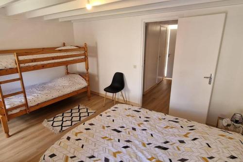 een slaapkamer met 2 stapelbedden en een stoel bij Petite maison de La Hague in Beaumont-Hague