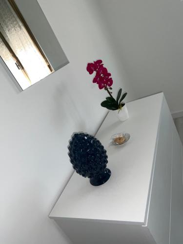 a vase with flowers sitting on a white table at Dolce Dormire in Enna