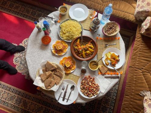a table with plates and bowls of food on it at ECOLODGE MISS ROSE CHEZ LA FAMILLE in Boumalne