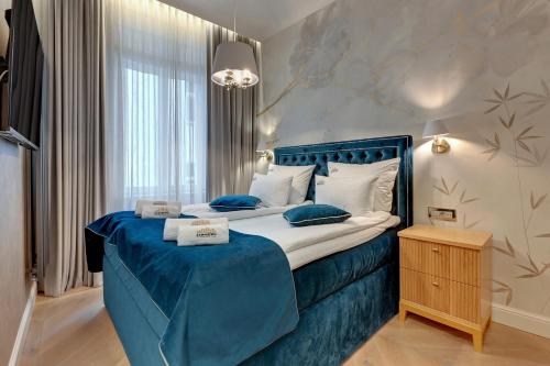 1 dormitorio con 1 cama grande con sábanas y almohadas azules en Sopot Pod Orłem Monte Cassino by Downtown Apartments en Sopot