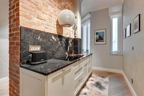 a kitchen with a sink and a brick wall at Sopot Pod Orłem Monte Cassino by Downtown Apartments in Sopot