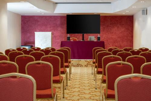 a conference room with red chairs and a screen at The Regent Boutique Hotel & Spa PRE OPENING in San Marino