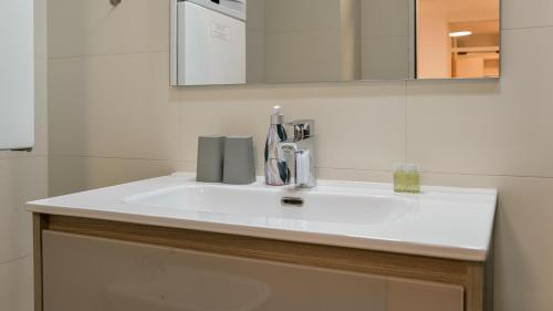 La salle de bains est pourvue d'un lavabo blanc et d'un miroir. dans l'établissement Deluxe City AS Apartment - FREE PARKING, à Zagreb