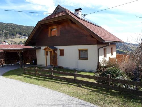 a house with a wooden roof and a fence at Chalet in Diex near Klopeiner See with sauna in Diex