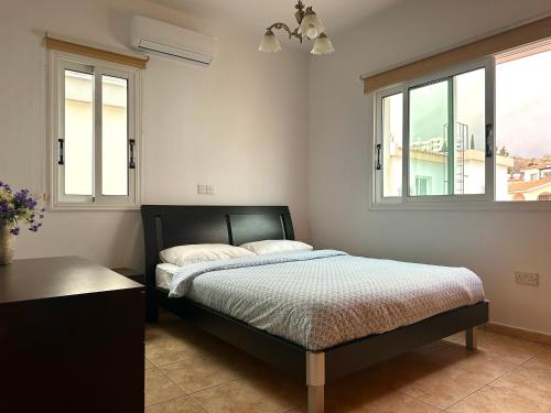 a bedroom with a bed and two windows at Athena Two-bedroom Townhouse in Paphos City