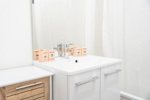 une salle de bain blanche avec un lavabo et un miroir dans l'établissement Le Réséda, maison avec jardin, à Saint-Valery-sur-Somme