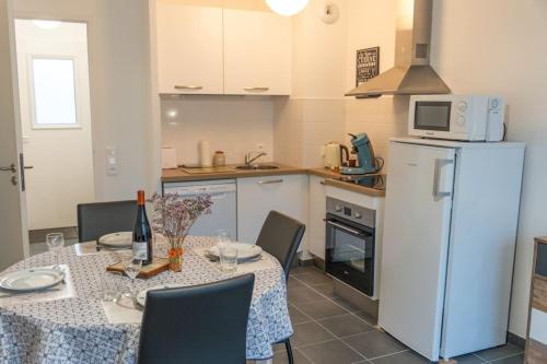 Il comprend une cuisine équipée d'une table et d'un réfrigérateur blanc. dans l'établissement Le Réséda, maison avec jardin, à Saint-Valery-sur-Somme