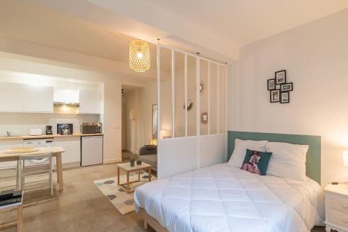une chambre avec un grand lit blanc et une cuisine dans l'établissement Le Sauge, Charmant Loft, Clim, Proche Comédie, à Montpellier