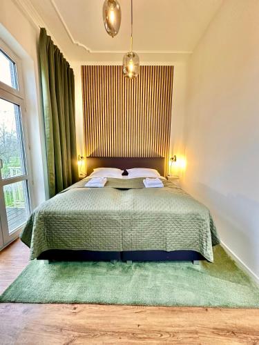 a bedroom with a large bed with a green blanket at Ferienhaus Weserblick am Sandstrand mit Dart, Billard und Tischkicker in Berne