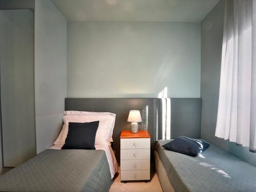a bedroom with two beds and a lamp on a night stand at Comosole in Como