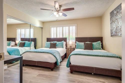 a bedroom with three beds and a ceiling fan at Luxury Vegas Home with 5BR, Casita, Hot Tub, and Pool in Las Vegas