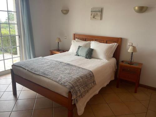 a bedroom with a large bed with two night stands at Casa Alves - Villa with private heated swimming pool in Olhos de Água