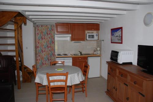 une cuisine avec une table et des chaises et une cuisine avec un four micro-ondes dans l'établissement VOTRE T3 à LUZ SAINT SAUVEUR, été hiver, à Luz-Saint-Sauveur