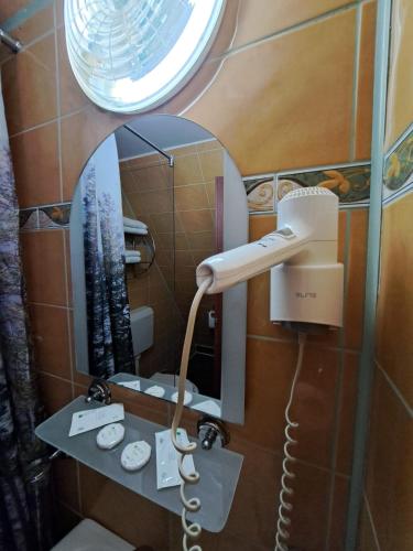 a bathroom with a hair dryer and a mirror at Hotel Pescarus Port Bicaz in Bicaz