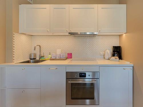 a kitchen with white cabinets and a sink at VacationClub - Leśna 12A Apartament 24 in Pobierowo