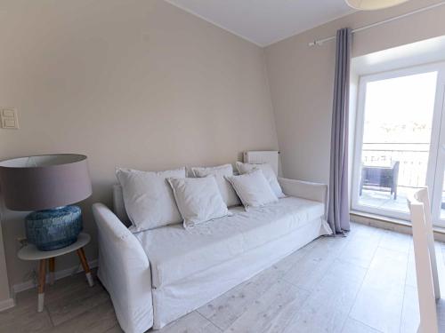 a white couch in a living room with a window at VacationClub - Leśna 12A Apartament 24 in Pobierowo