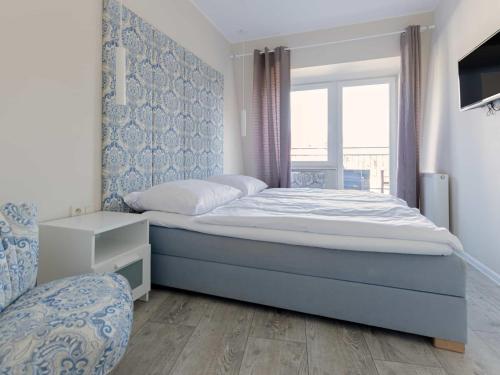 a bedroom with a large bed and a window at VacationClub - Leśna 12A Apartament 24 in Pobierowo