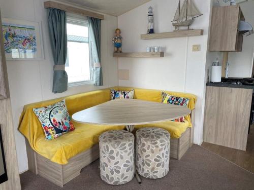 a table and a yellow couch in a room at 23 The Lawns Pevensey Bay Holiday Park in Pevensey