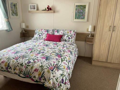 een slaapkamer met een bed met een bloemenbed bij 23 The Lawns Pevensey Bay Holiday Park in Pevensey