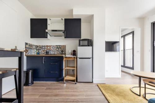a kitchen with blue cabinets and a white refrigerator at L'Escapade Paris in Le Kremlin-Bicêtre
