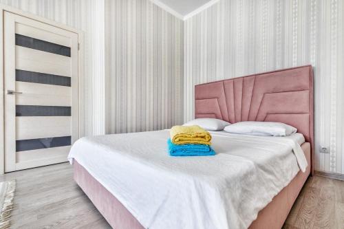 um quarto com uma cama rosa com uma toalha amarela em HOST Apart-otel em Taldykolʼ