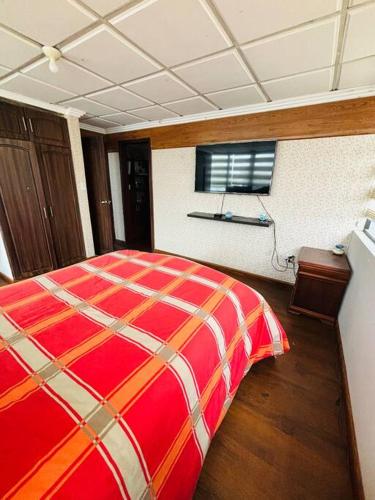 a bedroom with a red bed and a window at Departamento Torre Azul in Cuenca