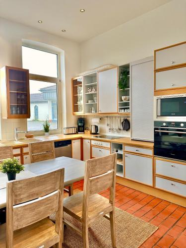 cocina con mesa, sillas y ventana en Ferienhaus Weserblick am Sandstrand mit Dart, Billard und Tischkicker, en Berne