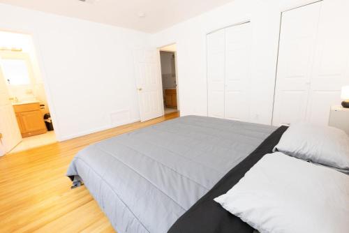 a white bedroom with a large bed and wooden floors at Stylish & Spacious 3-bed Apt mins to NYC in Jersey City