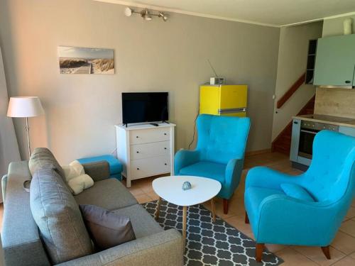 a living room with a couch and two blue chairs at Tjarkshof in Friedrichskoog