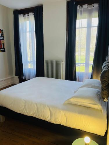 a bed in a bedroom with blue curtains and a window at Opal'House Face aux Remparts in Boulogne-sur-Mer