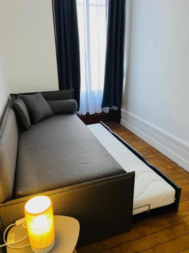 a couch sitting in a living room with a lamp at Opal'House Face aux Remparts in Boulogne-sur-Mer