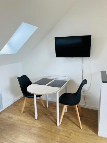 a white table with two chairs and a tv on a wall at Opal'House Face aux Remparts in Boulogne-sur-Mer