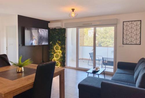 a living room with a blue couch and a table at Marcenac - T2 en Résidence, Clim, Parking, terrasse in Sète