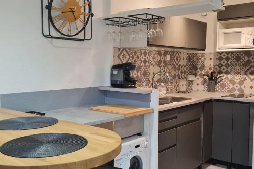 une cuisine avec une table et une horloge au mur dans l'établissement Une pépite au calme, vue mer, port, Piscine, au Cap d'Agde