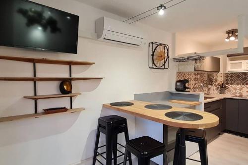 Il comprend une cuisine avec une table et une télévision murale. dans l'établissement Une pépite au calme, vue mer, port, Piscine, au Cap d'Agde