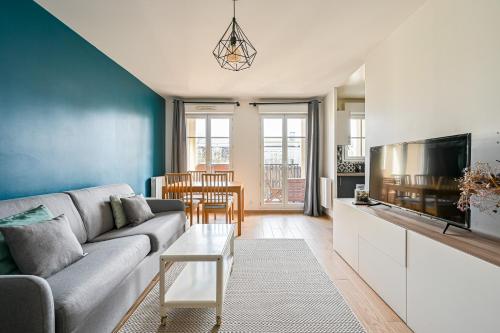 un salon avec un canapé et une télévision dans l'établissement Le Fantasia - Disney - Parking - Wifi, à Bussy-Saint-Georges