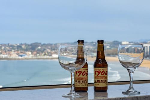 two bottles of beer and two glasses on a table at Bustos Home Apartamento in Gijón