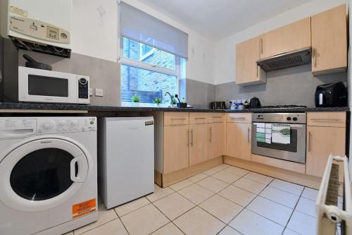 a kitchen with a dishwasher and a washer at Charsley Lodge in London