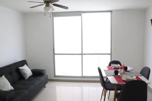 ein Wohnzimmer mit einem schwarzen Sofa und einem Tisch in der Unterkunft Cómodo Apartamento Amoblado en Condominio in Cúcuta