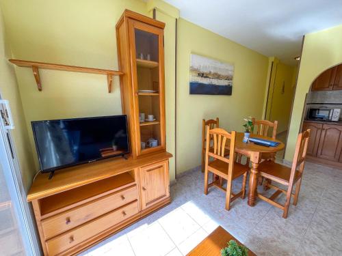 a living room with a television and a dining room table at Apartamentos Costa Azahar 3000 in Alcossebre