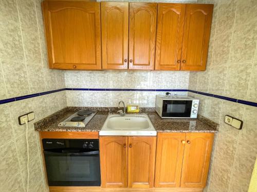 a small kitchen with a sink and a microwave at Apartamentos Costa Azahar 3000 in Alcossebre