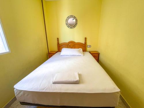 a small bedroom with a bed with a white blanket at Apartamentos Costa Azahar 3000 in Alcossebre