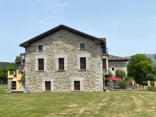 ein großes Steingebäude mit einem Rasenhof in der Unterkunft Casa BellaTerra in Villasana de Mena