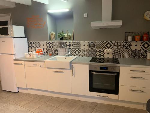 Il comprend une cuisine équipée d'appareils électroménagers blancs et d'un réfrigérateur blanc. dans l'établissement Les Bâtisses de Clément, à Clelles
