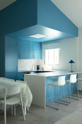 a kitchen with blue cabinets and a table and chairs at A Casa da Porta Azul in Porches