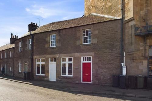 a brick building with a red door on a street at The Old Post Office House in Perth