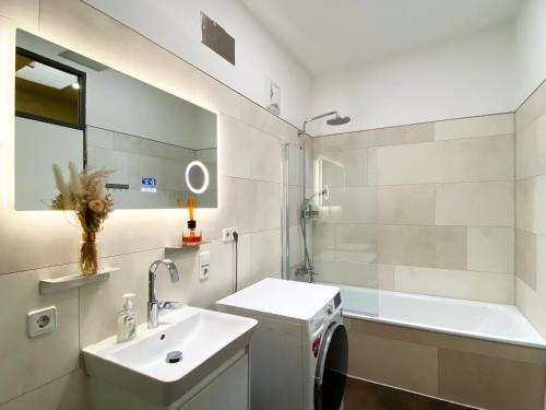 a white bathroom with a sink and a bath tub at Exklusives Leipzig City Apartment Sunrise in Leipzig